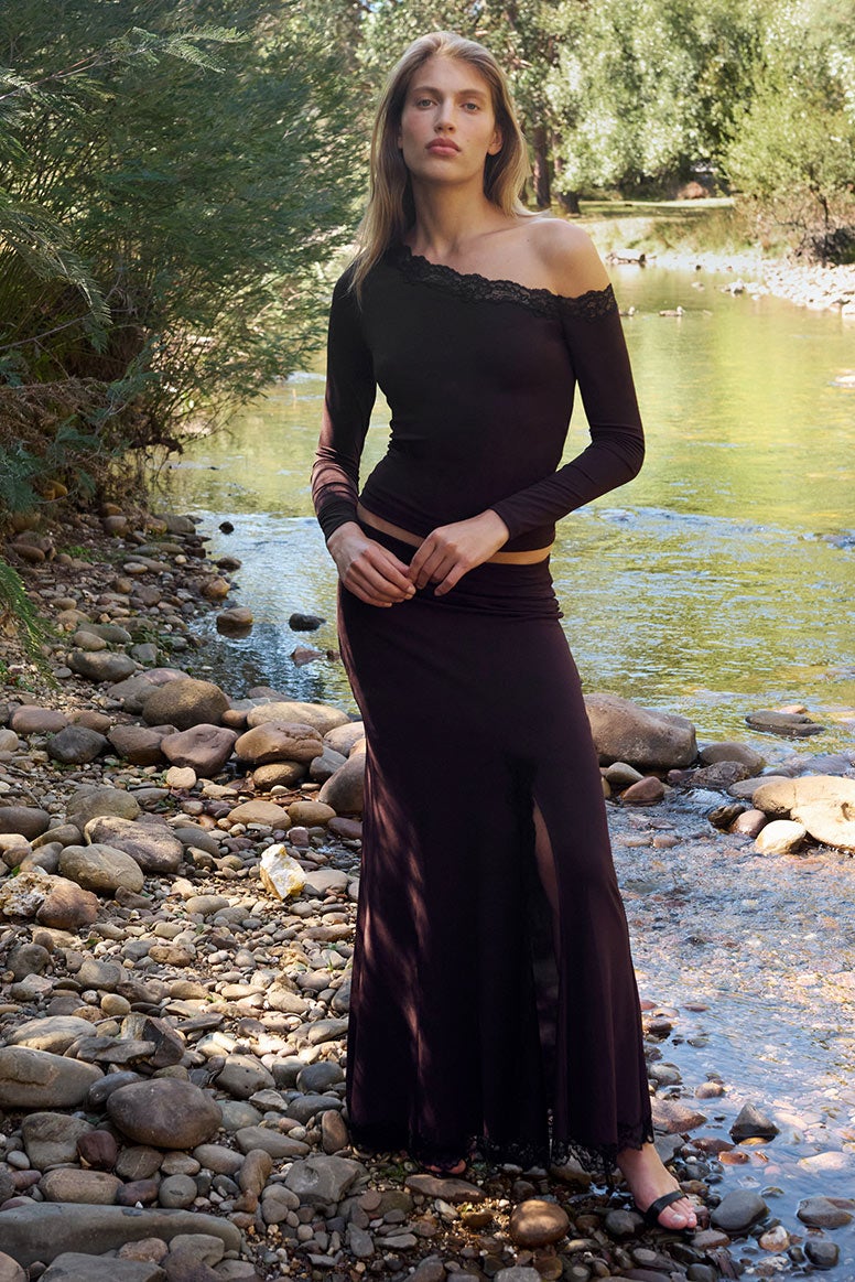 Model wears matching set with black lace detailing, off shoulder neckling and long maxi skirt for a flattering autumn/winter look.